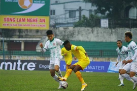 Một pha xử lý bóng của cầu thủ Sông Lam Nghệ An (áo vàng) trước các cầu thủ Bình Định. (Ảnh: Tá Chuyên - TTXVN)