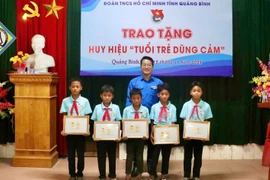 Phó Bí thư Tỉnh Đoàn, Chủ tịch Hội đồng Đội tỉnh Quảng Bình trao tặng Huy hiệu Tuổi trẻ dũng cảm cho 5 em học sinh. (Nguồn: Báo Pháp Luật)