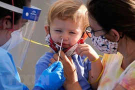Nhân viên y tế lấy mẫu xét nghiệm COVID-19 cho trẻ em ở Brooklyn, New York (Mỹ). (Ảnh: The New York Times/TTXVN) 