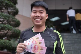 Vẻ mặt hạnh phúc khi được sở hữu đồng tiền kỷ niệm. (Ảnh: Minh Sơn/Vietnam+)