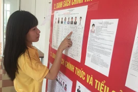 Công nhân tìm hiểu thông tin về các đại biểu. (Ảnh: Hồng Kiều/Vietnam+)