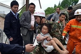 Nhân viên cứu hộ đưa một em bé ra khỏi ngôi nhà sập sau trận động đất ở tỉnh Tứ Xuyên. (Nguồn: THX/TTXVN)