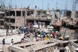 Nhân viên cứu hộ và tình nguyện viên tham gia cứu hộ sau vụ sập nhà. (Ảnh: AFP/TTXVN)