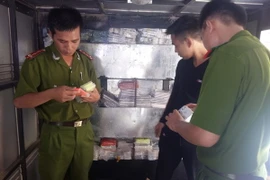 Lực lượng công an đang kiểm tra nguồn gốc xuất xứ số điện thoại di động thu giữ trên ôtô tải BKS 14C-134.37. (Ảnh: Thái Hùng/TTXVN)