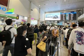 Hành khách xếp hàng làm thủ tục tại Sân bay Tân Sơn Nhất. (Ảnh: Tiến Lực/TTXVN)