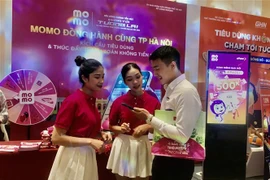 Người tiêu dùng hào hứng với ứng dụng thanh toán điện tử không dùng tiền mặt tại Sự kiện. (Ảnh: Phương Anh/TTXVN)