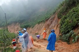 Các lực lượng xung kích và người dân địa phương dọn dẹp đất đá bị sạt lở trên các tuyến đường liên xã Trà Vân-Trà Cang, huyện Nam Trà My, tỉnh Quảng Nam. (Ảnh: Đoàn Hữu Trung/TTXVN)