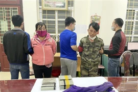 Hai đối tượng Cư Chiếu và Hờ Thị Xày cùng tang vật tại cơ quan cảnh sát điều tra. (Ảnh: TTXVN phát)