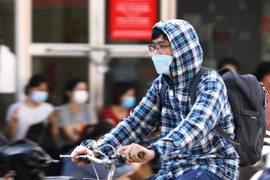 Người dân sử dụng quần áo chống nóng khi phải di chuyển ngoài trời. (Ảnh: Hoàng Hiếu/TTXVN)