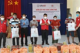 Đại diện Hội Chữ thập đỏ Việt Nam và chính quyền địa phương trao nhu yếu phẩm cho các hộ dân. (Ảnh: TTXVN phát)