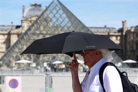 Người dân che ô bảo vệ trong thời tiết nắng nóng tại Paris, Pháp. (Ảnh: THX/TTXVN)
