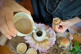 Thưởng thức một ấm trà sen sớm mai. (Ảnh: Xuân Mai/Vietnam+)