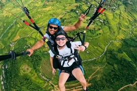 Du khách bay đôi cùng phi công để trải nghiệm ngắm cảnh đẹp ruộng bậc thang mùa lúa chín ở Mù Cang Chải, Yên Bái. (Ảnh: TTXVN phát)