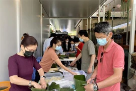 Các thành viên trong tổ gói bánh chưng gây quỹ hỗ trợ trẻ em nghèo tại Việt Nam. (Ảnh: Nguyễn Minh/TTXVN)