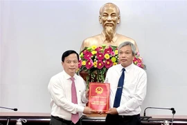 Phó Chủ tịch Thường trực UBND tỉnh Bình Định Nguyễn Tuấn Thanh (trái) trao quyết định cho ông Đặng Vĩnh Sơn. (Ảnh: Nguyên Linh/TTXVN)