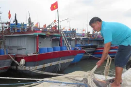 Ngư dân dùng dây neo cột tàu vào các trụ sắt ở trên bờ. (Ảnh: Tường Vi/TTXVN)