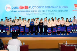 Đại diện Ban tổ chức với các tân sinh viên, học sinh Thành phố Hồ Chí Minh và các tỉnh miền Đông Nam bộ nhận học bổng “Tiếp sức đến trường” năm học 2021-2022. (Ảnh: Thanh Vũ/TTXVN)