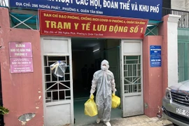Lực lượng Quân y tại Trạm y tế lưu động số 1 (phường 6, quận Tân Bình) mang các đồ dùng cần thiết (bình oxy, máy đo nồng độ oxy, ống nghe, nhiệt kế, dung dịch sát khuẩn, khẩu trang…) đến nhà F0. (Ảnh: Mạnh Linh/TTXVN)