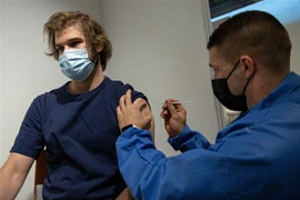 Nhân viên y tế tiêm vaccine ngừa COVID-19 cho thanh niên tại trung tâm tiêm chủng dã chiến ở Paris, Pháp. (Ảnh: THX/TTXVN)