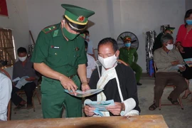 Bộ đôi Biên phòng Lào Cai phát tờ rơi tuyên truyền cho người dân về dịch COVID-19. (Ảnh TTXVN phát)