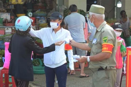 Người dân Đà Nẵng xếp hàng, rửa tay bằng nước sát khuẩn, đo thân nhiệt và bắt buộc đeo khẩu trang trước khi vào chợ. (Ảnh: Văn Dũng/TTXVN)