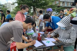 Người dân khu phố 1, phường 15, quận Gò Vấp khai báo y tế trước khi được lấy mẫu xét nghiệm COVID-19. (Ảnh: TTXVN phát)