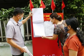 Người dân tham khảo danh sách đại biểu ở khu dân cư. (Ảnh: Nam Sương/TTXVN)