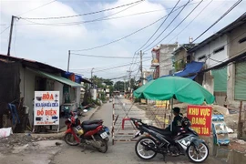 Lực lượng chức năng phong tỏa một đoạn đường TL19 (Khu phố 3B, phường Thạnh Lộc, Quận 12, Thành phố Hồ Chí Minh). (Ảnh: Tiến Lực/TTXVN)