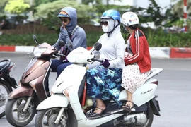 Người dân ra đường cần trang bị áo chống nắng, dụng cụ cần thiết. (Ảnh: Minh Quyết/TTXVN)