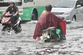 Nước ngập sâu khiến nhiều phương tiện chết máy, người dân phải dẫn bộ. (Ảnh: Hồng Giang/TTXVN)