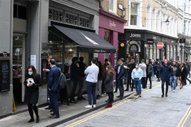 Người dân xếp hàng mua đồ bên ngoài một cửa hàng ở London (Anh). (Ảnh: AFP/TTXVN)