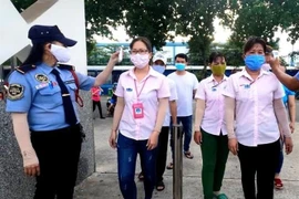 Công nhân vào ca đều đeo khẩu trang và được kiểm tra thân nhiệt. (Ảnh: Chí Tưởng/TTXVN)