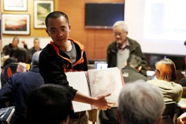 Kiến trúc sư Đoàn Bắc giới thiệu tư liệu trong bộ sưu tập cá nhân với những người bạn Nhật Bản đang sống và làm việc tại Hà Nội. (Ảnh: Vietnam+)