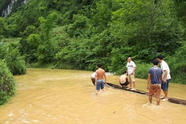 Người dân dùng bè mảng chở người qua đoạn đường bị ngập ở Cao Bằng. (Ảnh: Chu Hiệu/TTXVN)