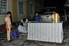 Kiểm tra tang vật trong một vụ bắt giữ thuốc lá lậu. (Ảnh: Văn Thông/TTXVN)