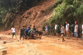 Lực lượng tại chỗ huyện Xín Mần giúp người dân di chuyển phương tiện qua các điểm sạt lở. (Ảnh: Kim Tiến/TTXVN phát)