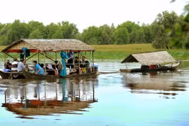 Du khách tham quan Vườn quốc gia Tràm Chim bằng nhà nổi trên sông. (Ảnh: An Hiếu/TTXVN)