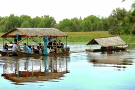 Du khách tham quan Vườn quốc gia Tràm Chim bằng nhà nổi trên sông. (Ảnh: An Hiếu/TTXVN)