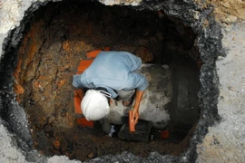 Nhân viên Công ty Thoát nước đô thị xử lý một hố tử thần (Ảnh: Mạnh Linh/TTXVN)