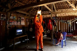 Công nhân Công ty Điện lực Thái Nguyên lắp đèn tiết kiệm điện và hướng dẫn người dân sử dụng điện an toàn. (Ảnh: Ngọc Hà/TTXVN)