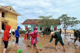 Giáo viên, phụ huynh học sinh và lực lượng thanh niên các đơn vị tại thị xã Ba Đồn, tỉnh Quảng Bình góp sức dọn dẹp, sửa chữa, vệ sinh các trường học bị thiệt hại sau bão số 10. (Ảnh: Võ Dung/TTXVN)