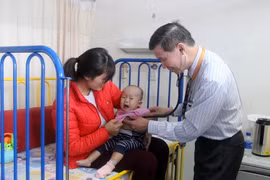 Bác sỹ Pau Kieu Kong đang thăm khám cho bệnh nhi. (Ảnh: Hoàng Nhương/Vietnam+)