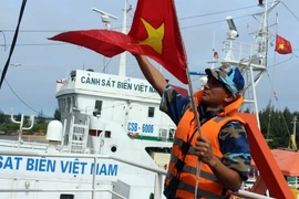 Chiến sỹ tàu Cảnh sát biển 9002 kéo cờ Tổ quốc, chuẩn bị xuất phát đi làm nhiệm vụ. (Ảnh: Đỗ Trưởng/TTXVN)