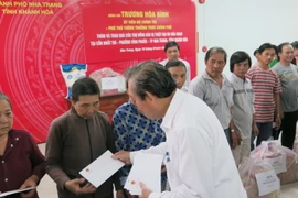 Phó Thủ tướng Trương Hòa Bình trao quà của Chính phủ cho các hộ dân bị thiệt hại về nhà cửa và tài sản trong vụ cháy. (Ảnh: Tiên Minh/TTXVN)