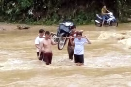 Người tham gia giao thông phải thuê người dân khênh xe máy qua các dập tràn đường ĐT 185 đoạn xã Xuân Vân, Kiến Thiết, huyện Yên Sơn với giá 50.000 đồng/lượt. (Ảnh: Quang Đán/TTXVN)
