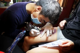Cường chăm chú với hình xăm thuộc loại khá khó đối với một thợ học việc (Ảnh: Thái Sương/Vietnam+)