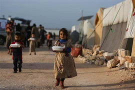 Trẻ tị nạn Syria nhận lương thực viện trợ từ một tổ chức từ thiện tại khu lều trại ở ngoại ô thị trấn Dana, phía Đông tỉnh biên giới Idlib. (Ảnh: AFP/TTXVN)