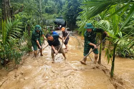 Cán bộ chiến sĩ Đồn biên phòng Phúc Sơn giúp người dân xã Phúc Sơn, huyện Anh Sơn khắc phụ hậu quả mưa lũ. (Ảnh: TTXVN phát)