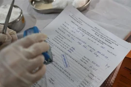 Đóng dấu cấp giấy chứng nhận đã tiêm vaccine phòng dịch COVID-19 cho người lao động. (Ảnh: Danh Lam/TTXVN)