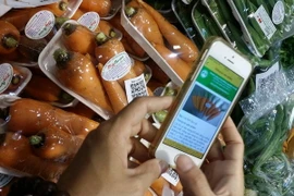 Người dân truy xuất nguồn gốc sản phẩm rau củ trên điện thoại thông minh. (Ảnh: Đỗ Phương Anh/TTXVN)
